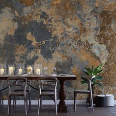 a dining room table with candles on it in front of a stone wall and floor