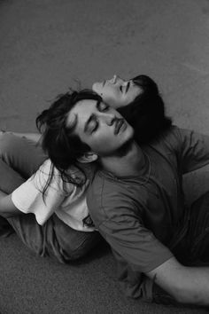 a man and woman laying on the ground with their heads close to each other's eyes