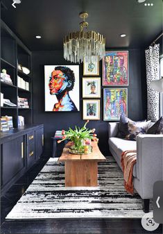 a living room with black walls and pictures on the wall above the couch, coffee table