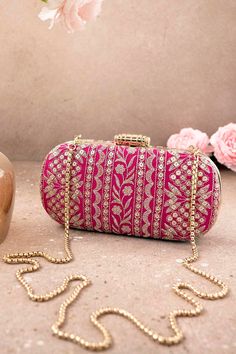 "Put together the perfect wedding look with our Mirai Embroidered clutch. This bag effortlessly delivers the Indian festive look. The luxe gold embroidery is a visual delight to the eyes. The gold tassels and the gold scallop lace add on to the grandeur of the bag. It's the perfect accessory for the bride to be who will be the center of attention.   Color: Pink with gold embroidery Dimensions (LxB): 8\"x4\" Handle length: 47\" Handle drop: 23\" Material: Embroidered poly silk, suede lining, golden metal clutch frame, golden metal sling. Features: metal lock closure, detachable metal sling." Luxury Gold Embroidered Clutch For Wedding, Luxury Wedding Clutch With Gold Embroidery, Festive Rectangular Clutch With Gold Embroidery, Luxury Embroidered Festive Bags, Bollywood Style Bags With Handwork For Reception, Rectangular Openable Clutch For Reception, Bollywood Style Handwork Bags For Reception, Festive Gift Potli Bag, Gold Festive Clutch For Festivals