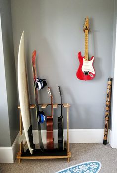 a surfboard and guitar hang on the wall next to a rack with two guitars