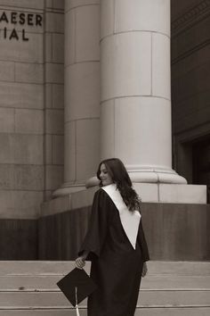 black and white photograph of woman in dress walking up steps with handbag on her hip