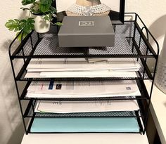 a stack of papers sitting on top of a desk next to a vase filled with flowers