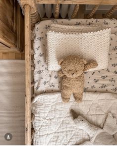 a brown teddy bear laying on top of a bed next to pillows and blankets in a room