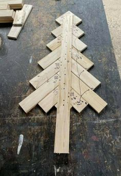 a wooden christmas tree sitting on top of a black table next to pieces of wood