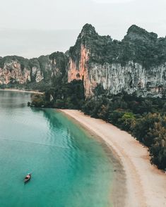 an aerial view of a boat on the water in front of some mountains and trees