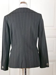 "This elegant French vintage black pinstriped women's blazer has a portrait-style neckline with wide peaked collar and a fitted waistline. The double-breasted jacket closes in the front with three large plexiglass and silver buttons and the words \"Paris couture\" inscribed (a total of six of those buttons appear on the front). The jacket has padded shoulders, and the long sleeves have the same decorative button on each cuff. The high-quality blazer is fully lined in black 100% acetate material Pinstripe Blazer, Elegant Jacket, Paris Couture, Double Breasted Jacket, European Vintage, Silver Buttons, Plaid Blazer, Vintage Summer, Quality Clothing