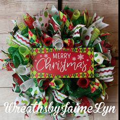 a christmas wreath with the words merry christmas on it and green, red and white bows