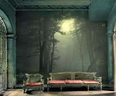 an empty room with a couch in front of a wall mural that has a forest scene on it