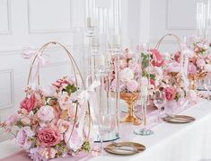 a table topped with lots of vases filled with pink flowers and candles next to each other