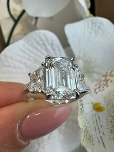 This 14K White Gold Engagement Ring features a stunning 4CT Emerald Cut Lab Grown Diamond Center Stone with Trapezoid Cut side stones of 0.75CT each. This engagement ring style is a true eye catcher. Metal Material: 14K White Gold Lab Grown Diamond: 4CT Emerald Shape Center and 0.75CT Each Trapezoid Cut Sidestones Shape: Emerald Cut & Trapezoid Cut Color: E Clarity: VS1 Cut: Excellent Dream Wedding Ring, Wedding Rings Princess Cut, Lab Grown Diamond Engagement Ring, Chic Rings, Future Engagement Rings, Lab Grown Diamonds Engagement, Dream Engagement Rings, Engagement Ring Styles, Ring Style