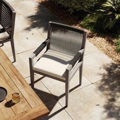 two chairs sitting next to each other near a wooden table with plates and glasses on it