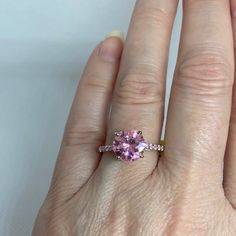 a woman's hand with a ring on it and a pink stone in the middle