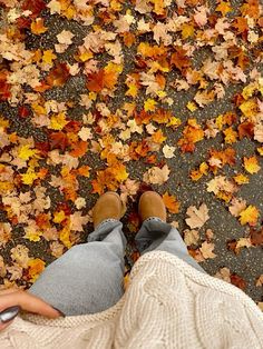 a person is standing in front of leaves on the ground with their feet propped up