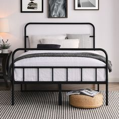 a black metal bed frame in a white bedroom with pictures on the wall above it