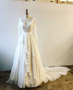 a white wedding dress on a mannequin in front of a wall and window