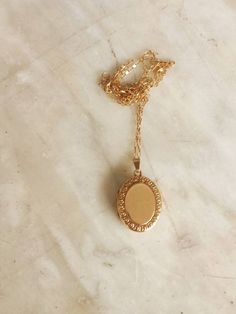 Early 20th century 9 ct gold oval  locket on a fine 9ct gold chain. The locket was made in the UK, probably around 1920, when the fashion changed from a preference for rose gold to yellow. It has a floral design framing the front; the back is plain. The locket is gold front and back; the frame and inside are of metal. The inside of the locket is intact, with room for a tiny photograph on  each side. The gold chain is a little later, probably c. 1930. Dainty Gold Oval Locket Necklace, Dainty Gold Oval Pendant Locket Necklace, Vintage Gold Oval Link Locket Necklace, Vintage Gold Locket Necklace With Oval Link, Gold Necklace With Vintage Oval Pendant Charm, Yellow Gold Locket Necklace With Oval Pendant, 14k Gold Oval Pendant Locket Necklace, Gold Necklace With Oval Pendant And Vintage Charm, Gold Engraved Oval Cabochon Necklace