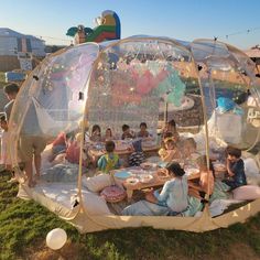 a group of people sitting around a table in a bubble tent