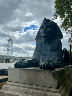 a statue of an egyptian pharaoh with a ferris wheel in the background