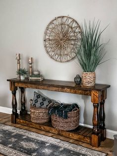 a wooden table with baskets and plants on it in front of a wall hanging decoration