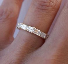 a woman's hand with a diamond ring on top of her finger and the band is