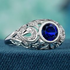 Add a delicate and unique aesthetic to your hand with this filigree ring crafted in elegant white gold, this exquisite ring showcases a breathtaking natural blue sapphire as its centerpiece. Intricate filigree detailing surrounding the sapphire enhances its allure, while multiple small diamonds adorn the ring, elevating its brilliance. With a design reminiscent of vintage elegance, this piece exudes timeless charm. Its beauty is truly captivating. CHARACTERISTICS Status: Made to order Origin: Th Elegant Sapphire Ring As Gift, Elegant Tanzanite Birthstone Ring For Promise, Elegant Lab-created Sapphire Ring For Wedding, Elegant Lab-created Sapphire Ring, Elegant Royal Blue Gemstone Rings, Elegant Royal Blue Sapphire Ring Gift, Elegant Royal Blue Sapphire Ring As Gift, Elegant Royal Blue Sapphire Ring With Center Stone, Heirloom Blue Sapphire Birthstone Ring