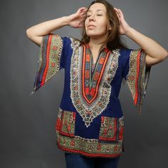 "Bright dashiki print shirt in rainbow colors on blue background. Made of cotton fabric, has wide 3/4 sleeves, side slits and notched neckline. Hippie style shirt. Two front pocket. Excellent vintage conditions. Fabric: 100% cotton Size: app. S / M but please check measurements of hips/ model M size ✂------m e a s u r e m e n t s-------------- Bust and waist already doubled. Bust: 39\" 99 cm Waist : 39\" 99 cm Hips: 39,5\" 100 cm Length: 28,5\" 72 cm Best way to know if it will fit? Compare the Blue Hippie V-neck Top, Multicolor Batik Print Short Sleeve Top, Bohemian Graphic Print Short Sleeve Blouse, Bohemian Blouse With Graphic Print And Short Sleeves, Bohemian Short Sleeve Blouse With Graphic Print, Blue Cotton Bohemian Tops, Multicolor Short Sleeve Tops With Batik Print, Bohemian Blue Cotton Tops, Blue Bohemian Cotton Tops