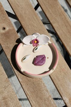 a white and pink flower sitting on top of a wooden bench