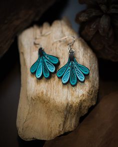 a pair of blue earrings sitting on top of a piece of wood