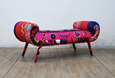 a colorful bench sitting on top of a hard wood floor next to a white wall