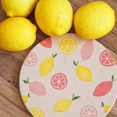 three lemons and two oranges on a plate next to some cut up lemons