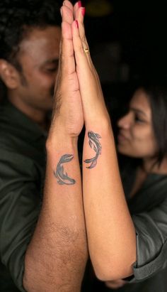 two people are holding hands together with tattoos on their arms and the other hand is raised up