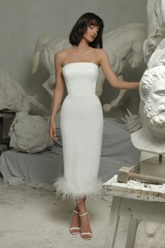 a woman in a white dress standing next to a statue