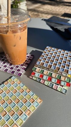 there is a drink on the table next to some coasters with squares in them