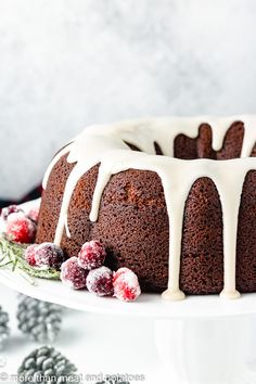 a bundt cake with icing and cranberries on a white platter