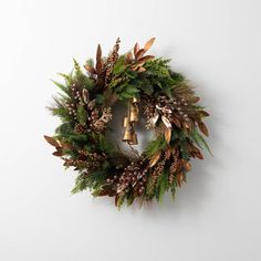 a wreath hanging on the wall with bells and greenery around it's edges