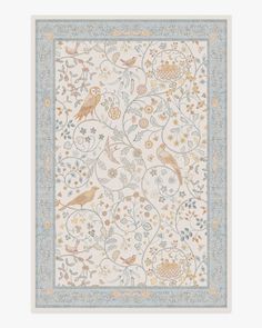 a white and blue rug with birds on the border, surrounded by floral vines and leaves