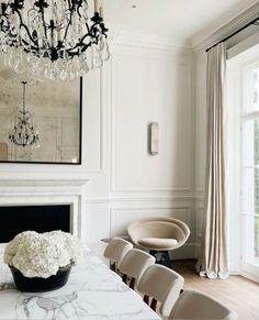 a dining room table with chairs and a chandelier hanging from it's ceiling