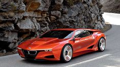 a red sports car driving down a road next to a stone wall and rock formations