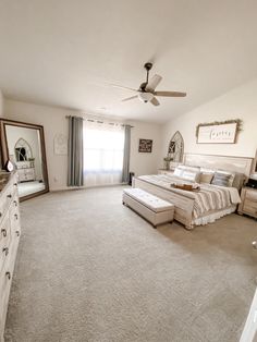 a bedroom with a large bed, dresser and ceiling fan in the middle of it