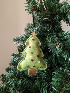 a green christmas tree ornament hanging from the top of a fir tree with stars on it