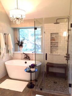 a white bath tub sitting next to a window in a bathroom under a chandelier