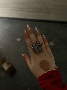 a woman's hand with brown nail polish on it and a ring in the middle