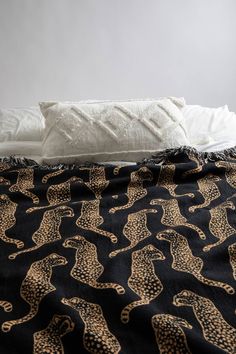 a bed with black and gold cheetah bedspread on top of it