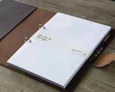 a notepad and pen sitting on top of a brown notebook with writing paper attached to it