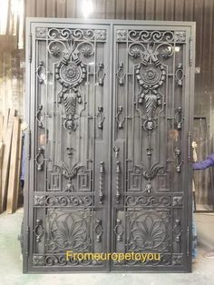 the man is standing in front of an ornate iron door with intricate carvings on it