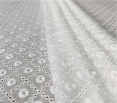 closeup of white fabric with small dots and circles on the bottom half of it