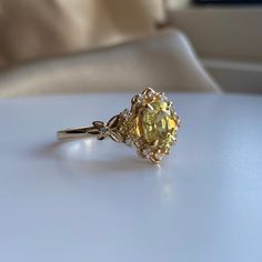 a yellow diamond ring sitting on top of a white table next to a pillow and chair