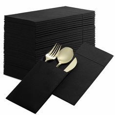 a stack of black napkins with gold forks and spoons on top of them