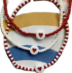 a red, white and blue striped purse with hearts on the front hanging from it's side